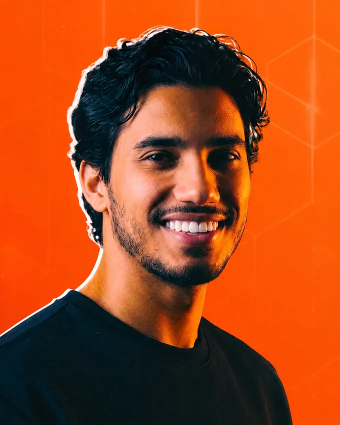 Kaique Salvador sorrindo, de camiseta preta, com fundo laranja